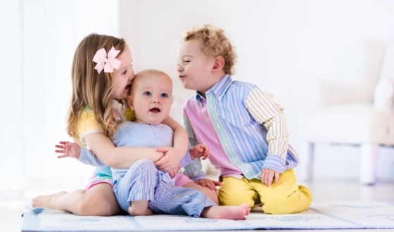 Dječak i djevojčica s bebom sjede na podu